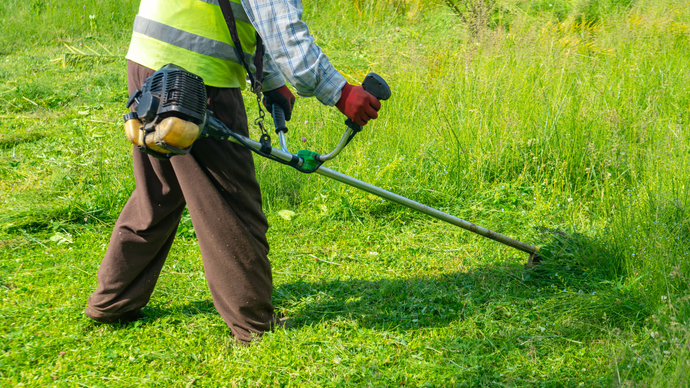 A man is cutting grass with a lawn mower in a field.