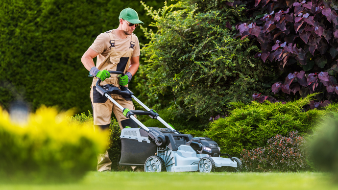 A man is mowing a lush green lawn with a lawn mower.