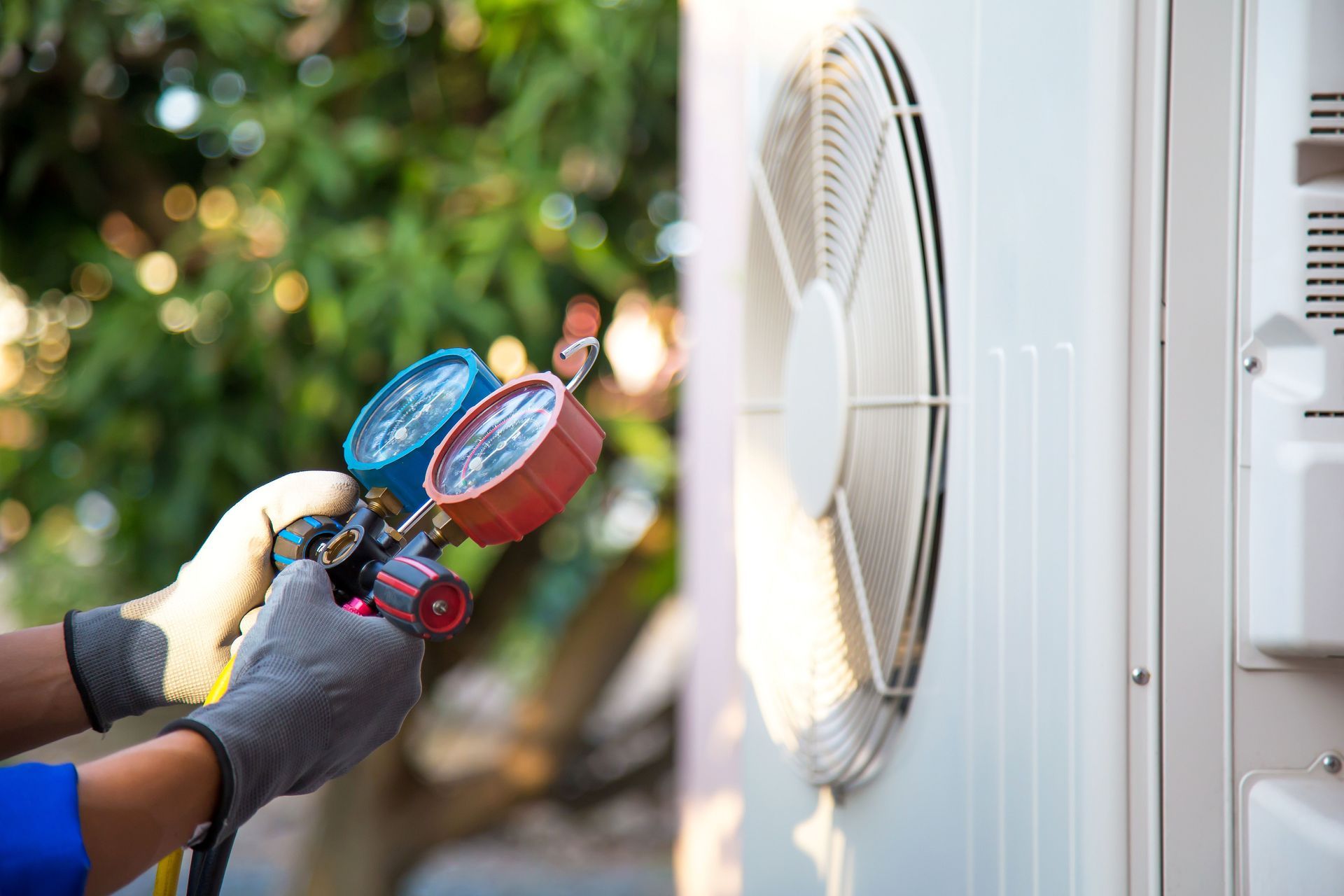 Technician using pressure gauges to check outdoor air conditioner unit.