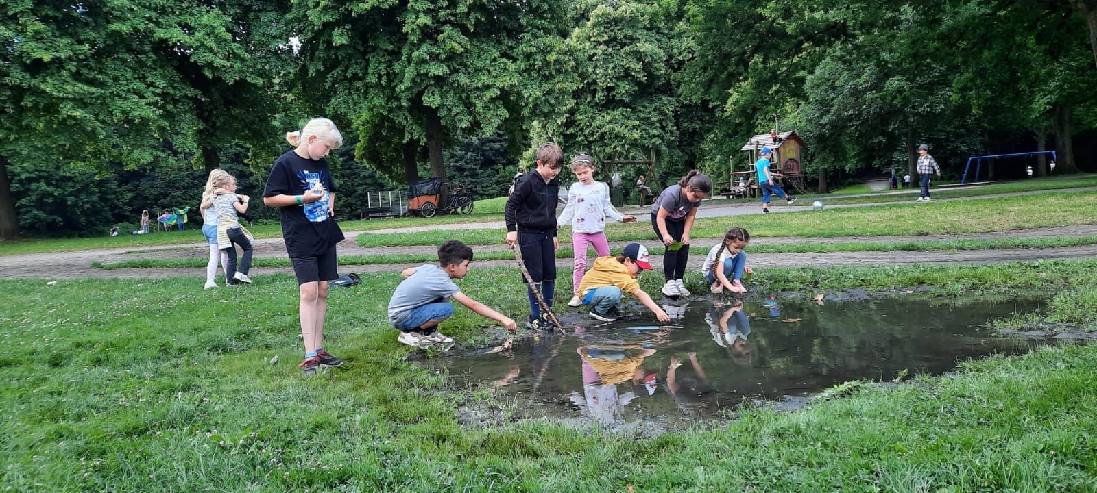 Schülerinnen der Schule Iserbrook beim Sommerausflug spielen in der Pfütze