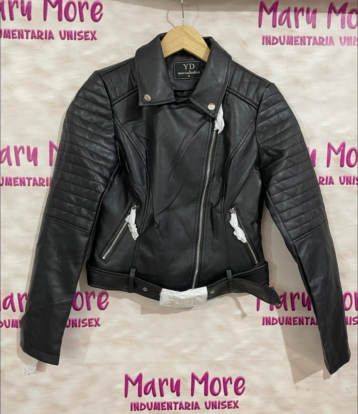 Una chaqueta de cuero negra está colgada en una percha de madera.