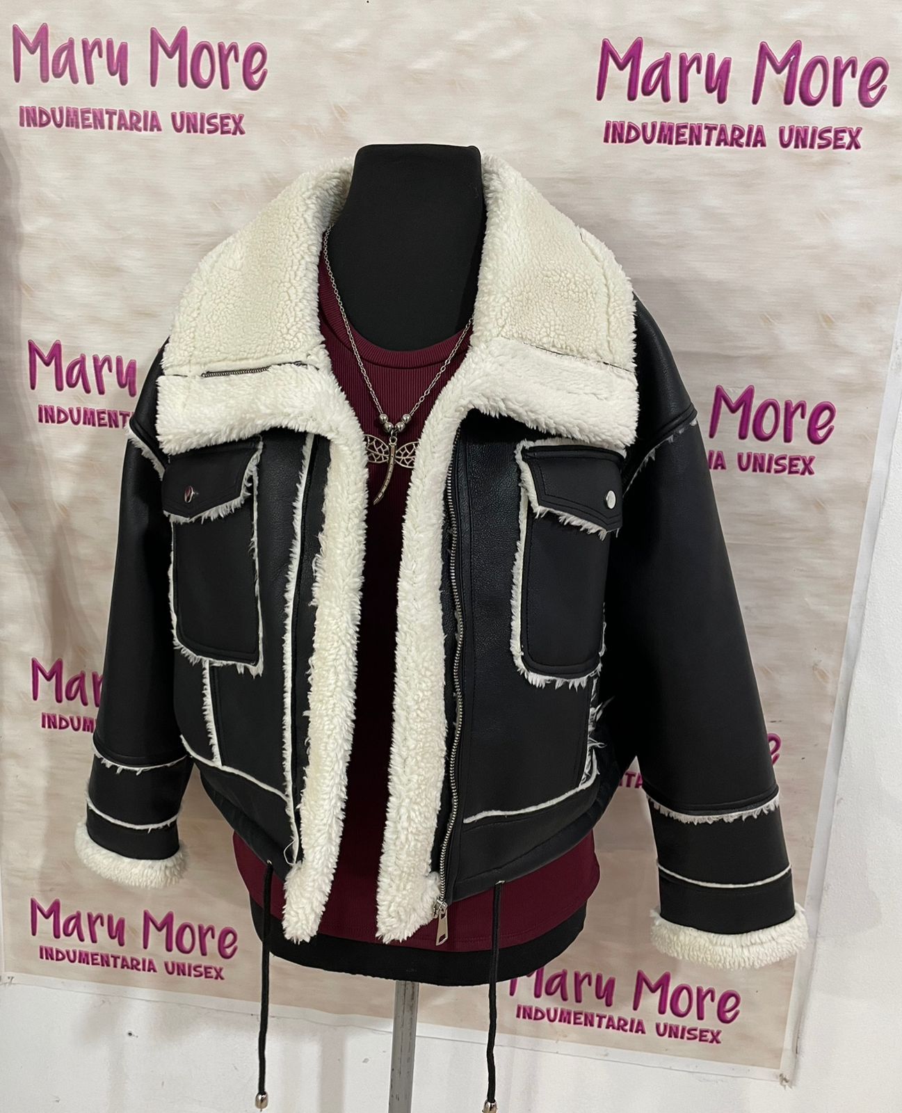 Una chaqueta negra con cuello blanco está colgada en una percha