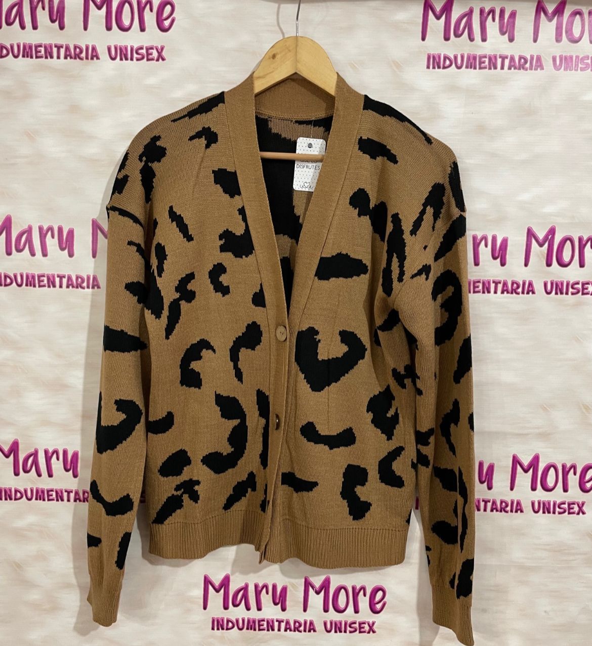 Un cárdigan verde con corazones negros cuelga de una percha.