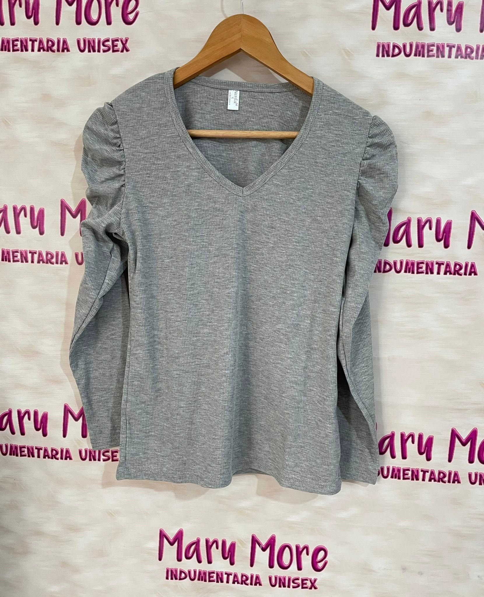 Una camisa negra con mangas con volantes cuelga de una percha.