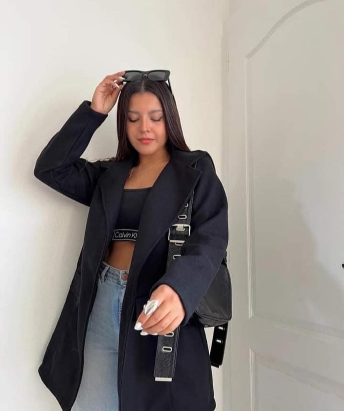 Una mujer lleva un abrigo gris y una falda negra.