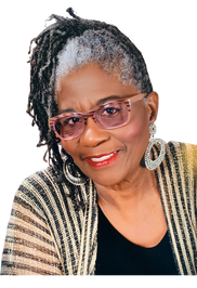 A woman with dreadlocks and glasses is smiling for the camera.