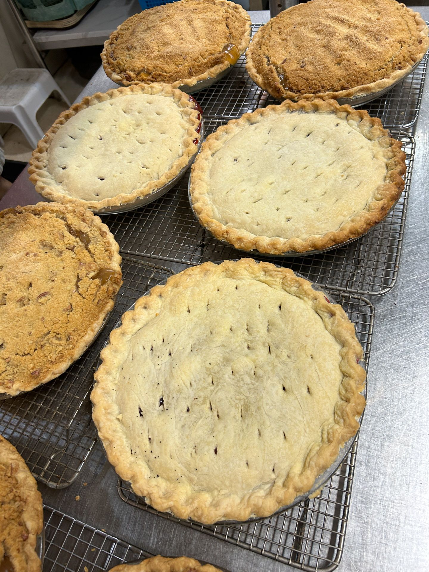 A bunch of pies are sitting on a cooling rack.