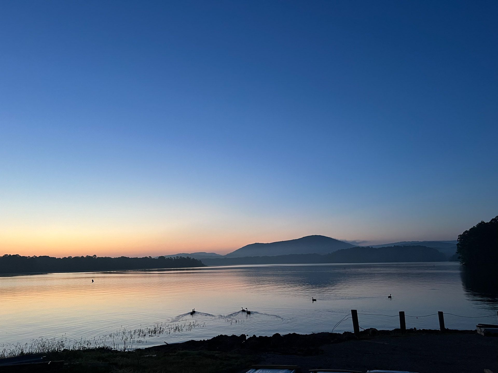 A large body of water with mountains in the background at sunset.