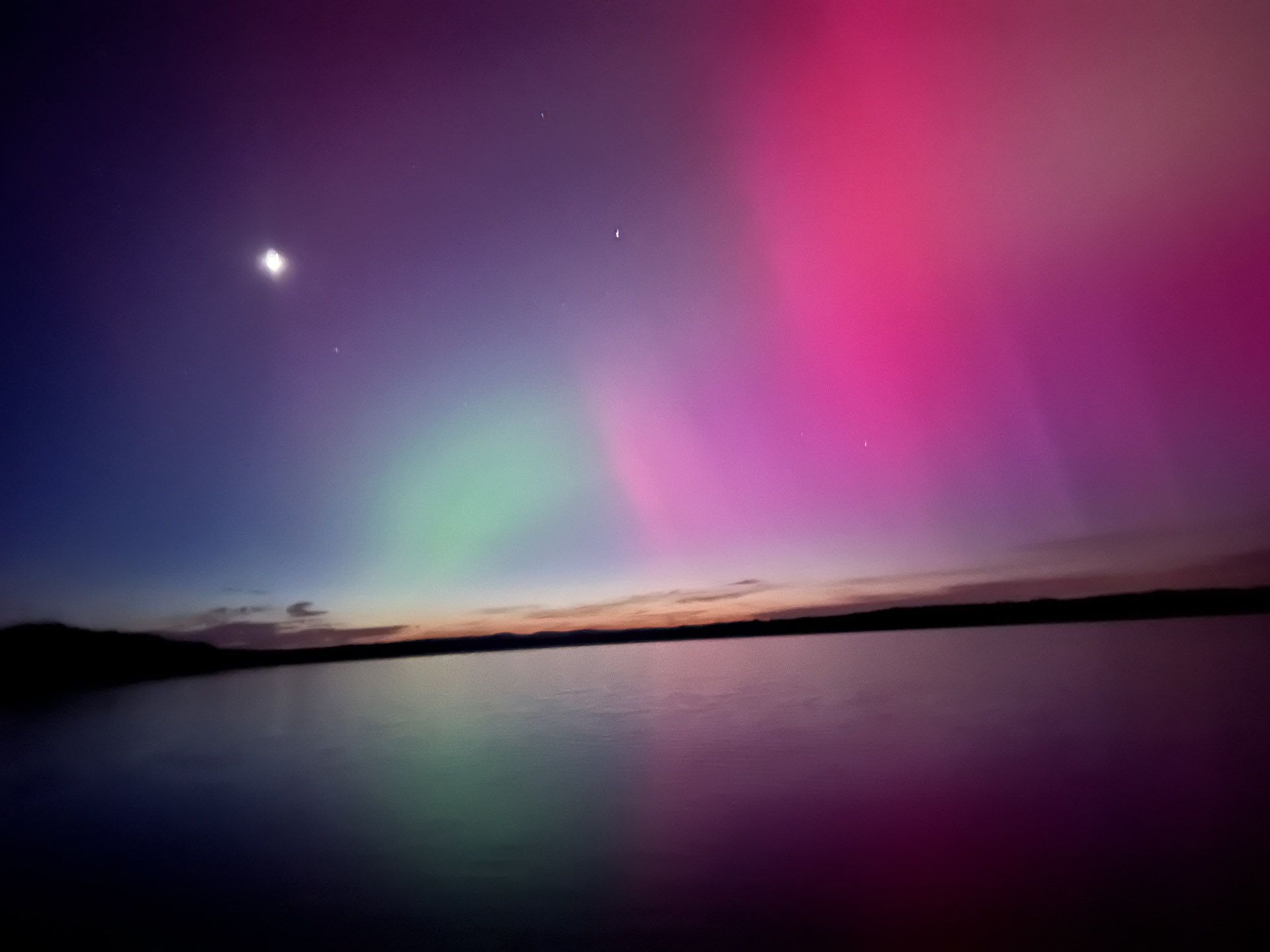 The aurora borealis is visible over a body of water