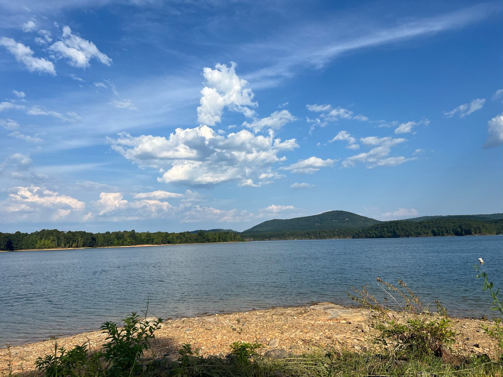 A large body of water with mountains in the background on a sunny day.