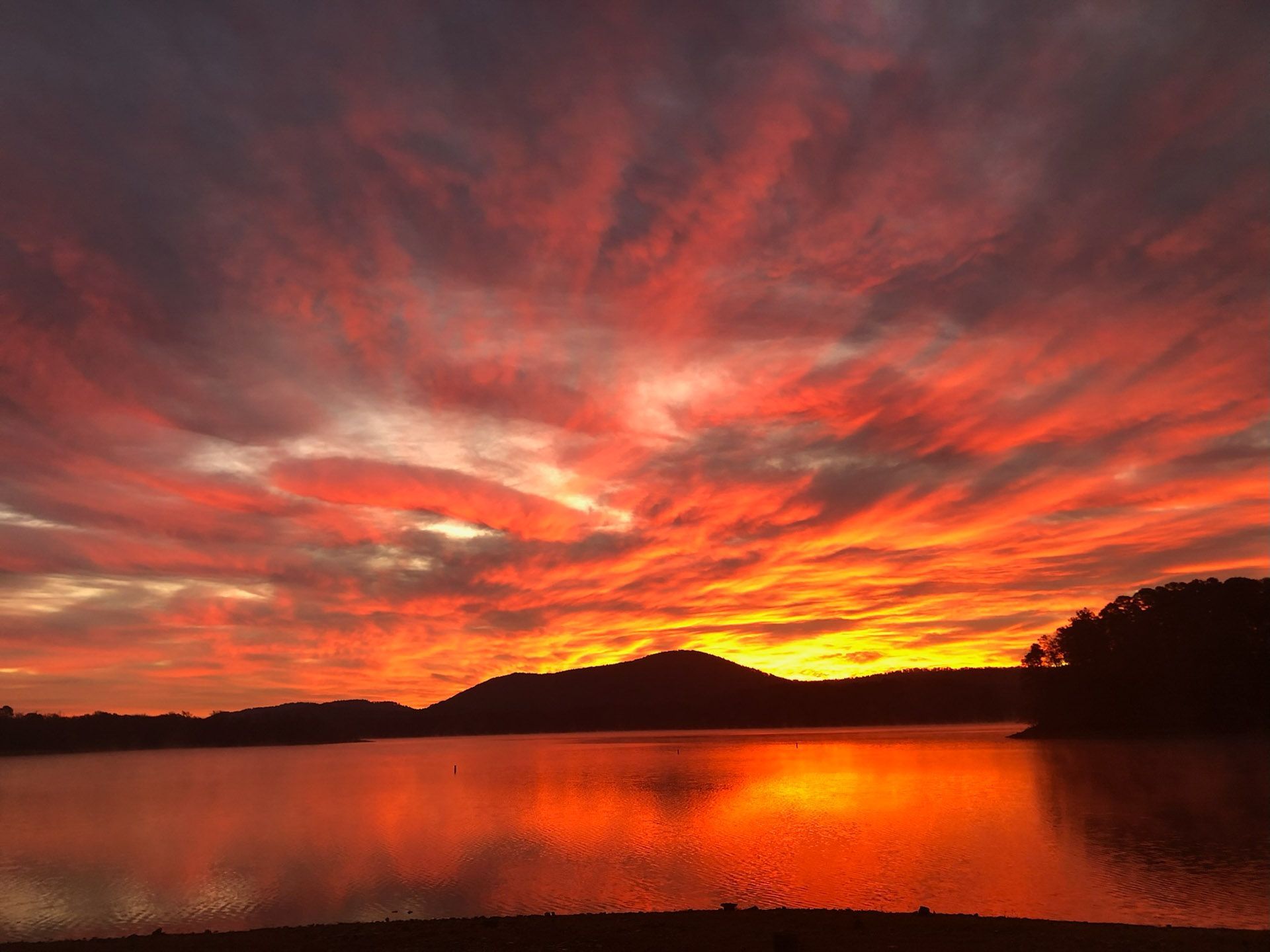 A sunset over a lake with mountains in the background