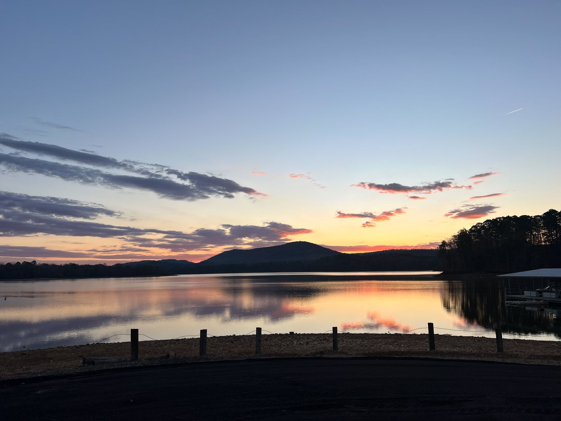 A sunset over a lake with a mountain in the background