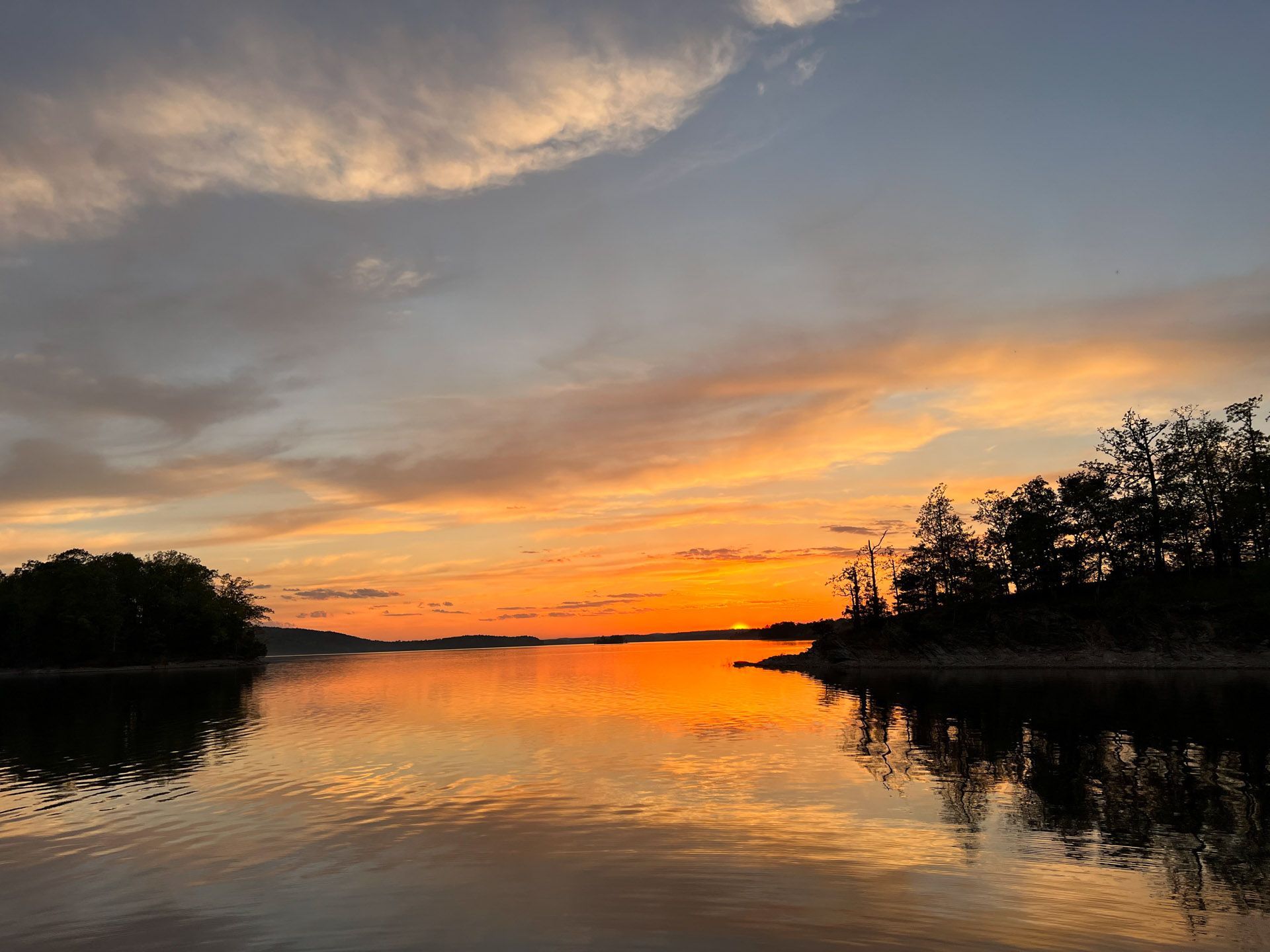 A sunset over a lake with trees in the foreground