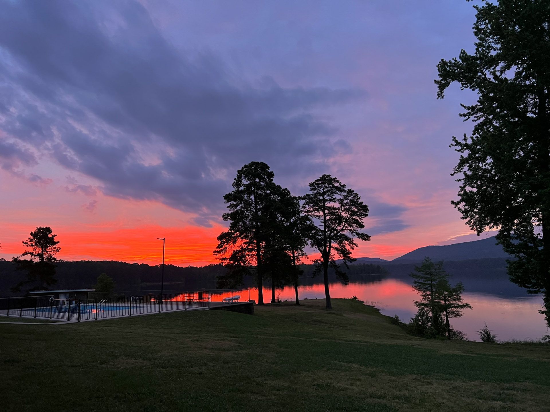 A sunset over a lake with trees in the foreground