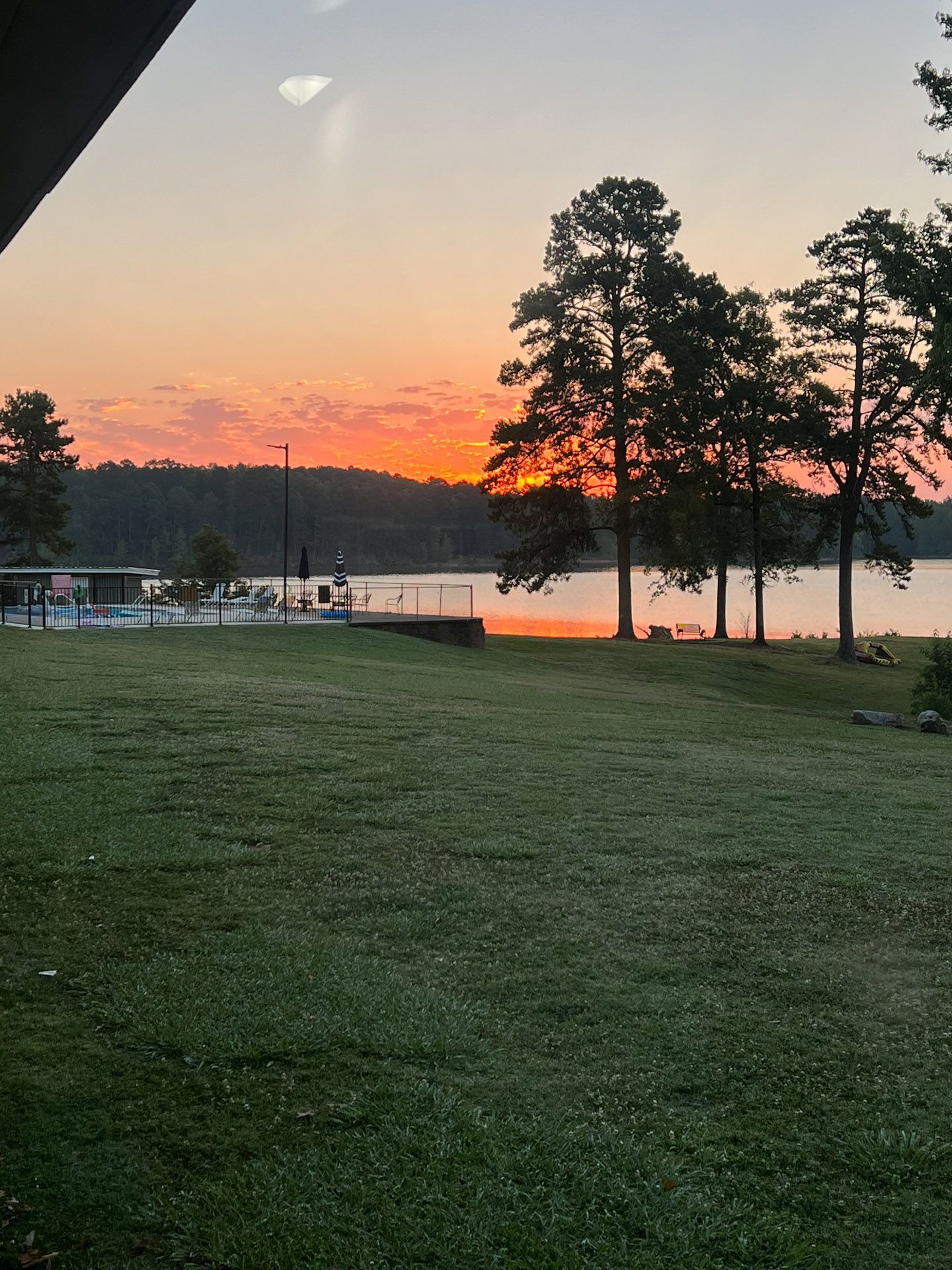 A sunset over a lake with trees in the foreground