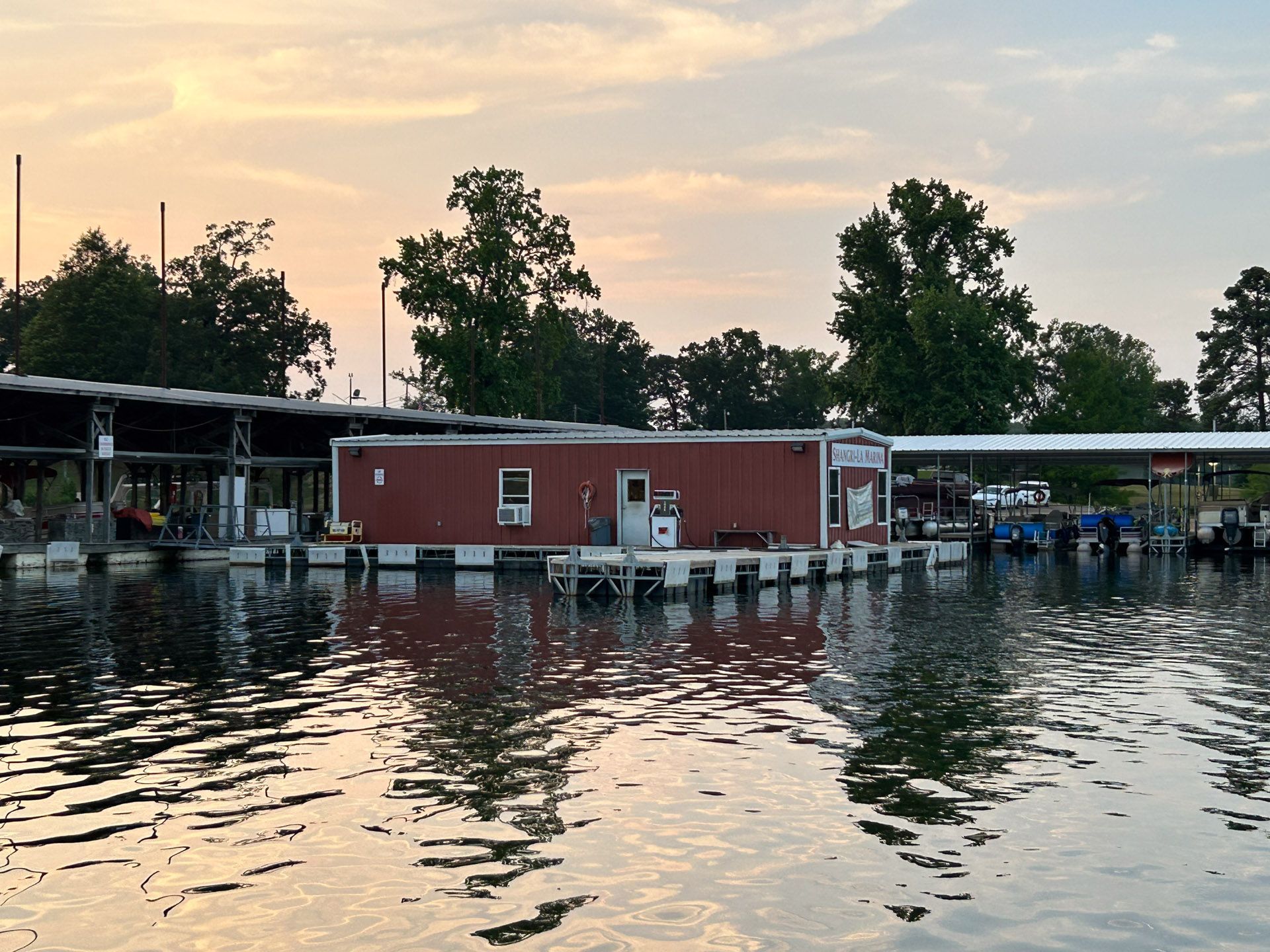 A red building sits on a dock in the middle of a body of water.