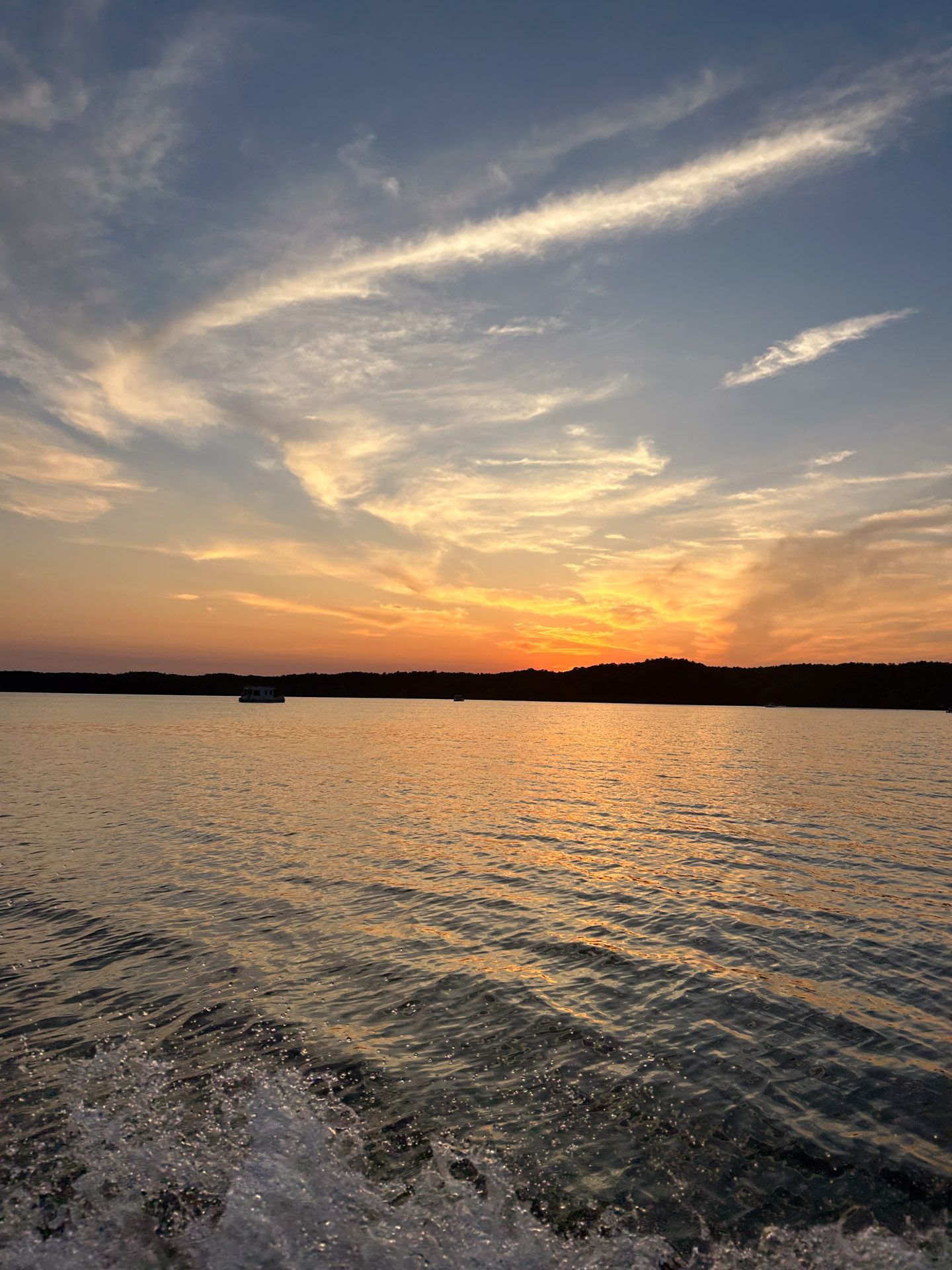 A boat is floating on a lake at sunset.