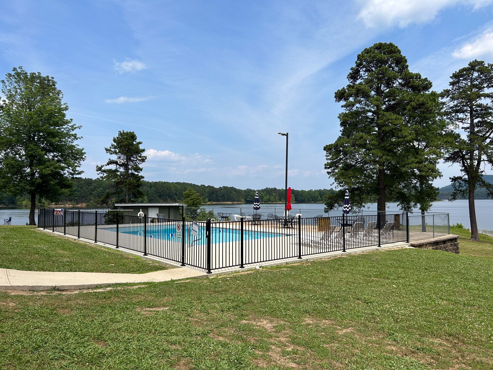 A swimming pool surrounded by a fence with a lake in the background