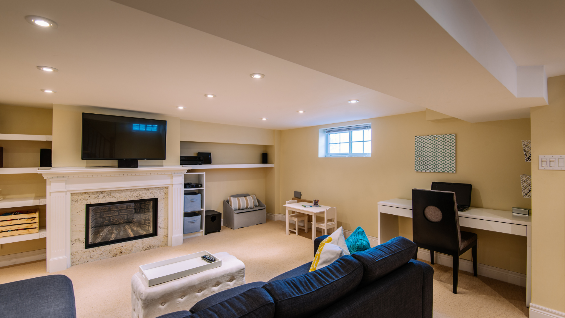 A living room with a couch , fireplace , desk and television.