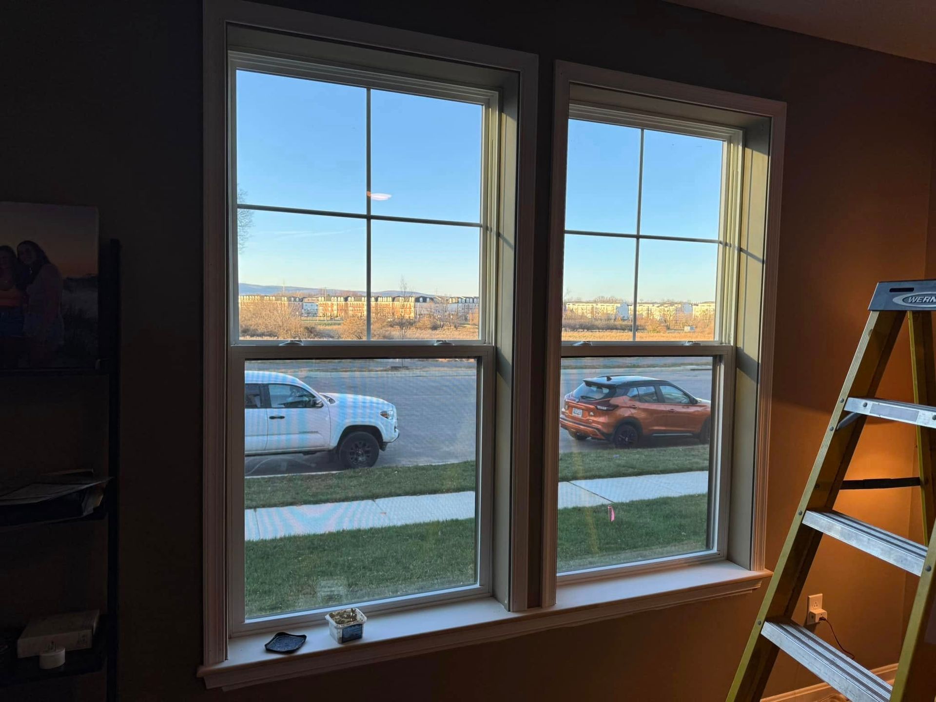 A room with two windows and a ladder in it.