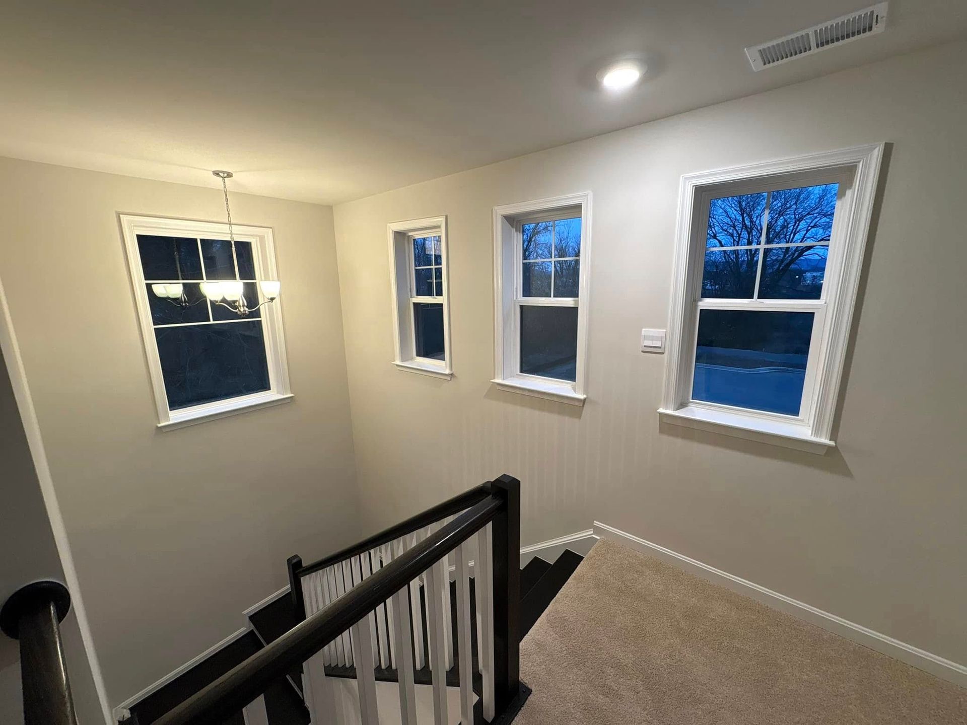 A staircase in a house with three windows and a railing.