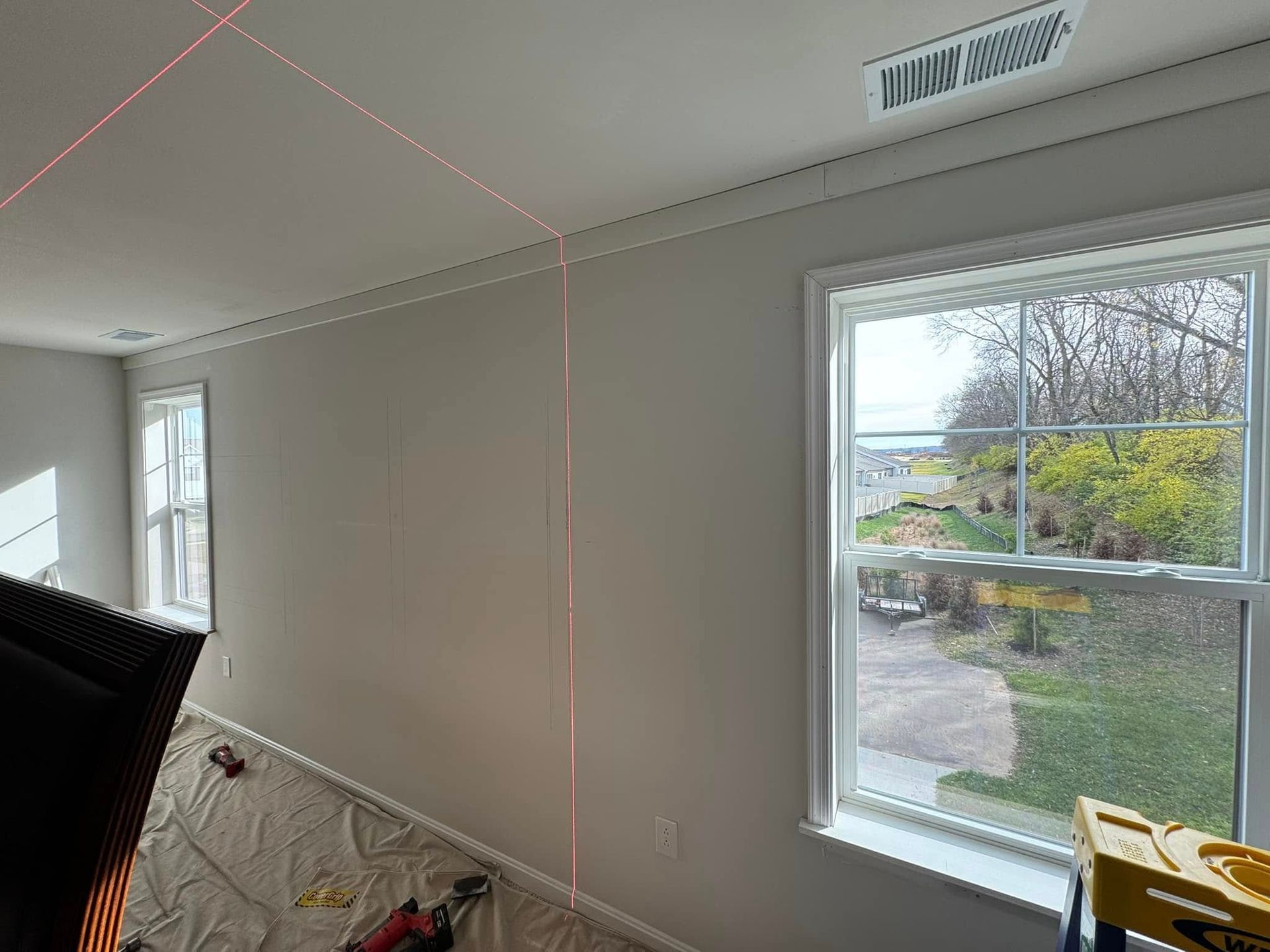 A person is using a laser level to measure a wall in a room.