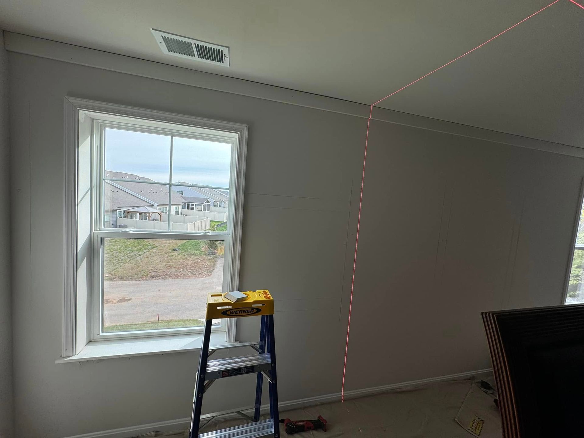 A room with a window and a ladder in it.