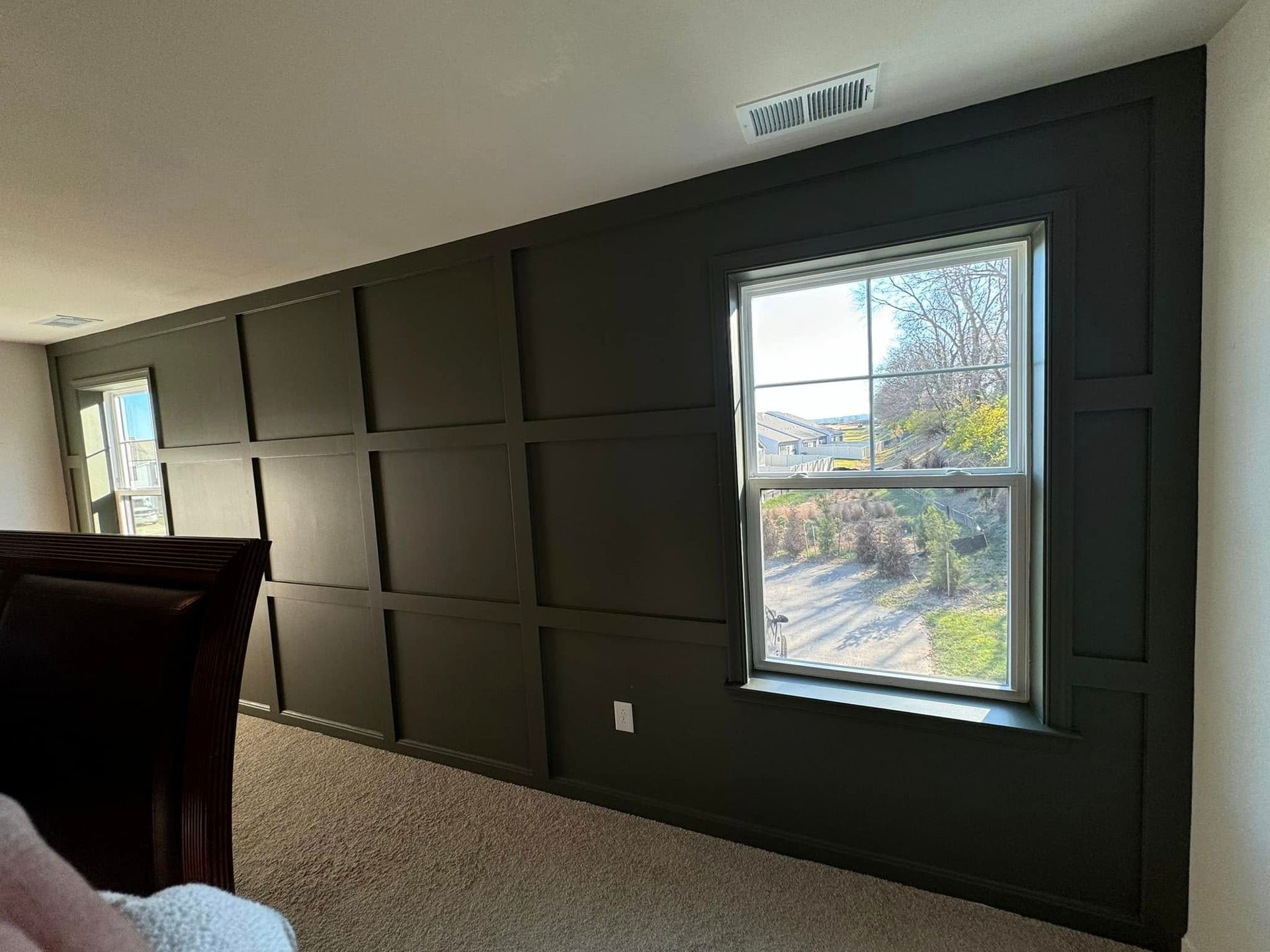 A bedroom with a black wall and two windows.