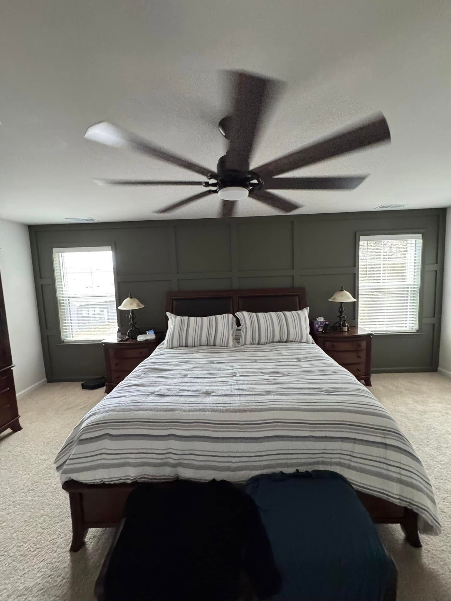 A bedroom with a large bed and a ceiling fan.