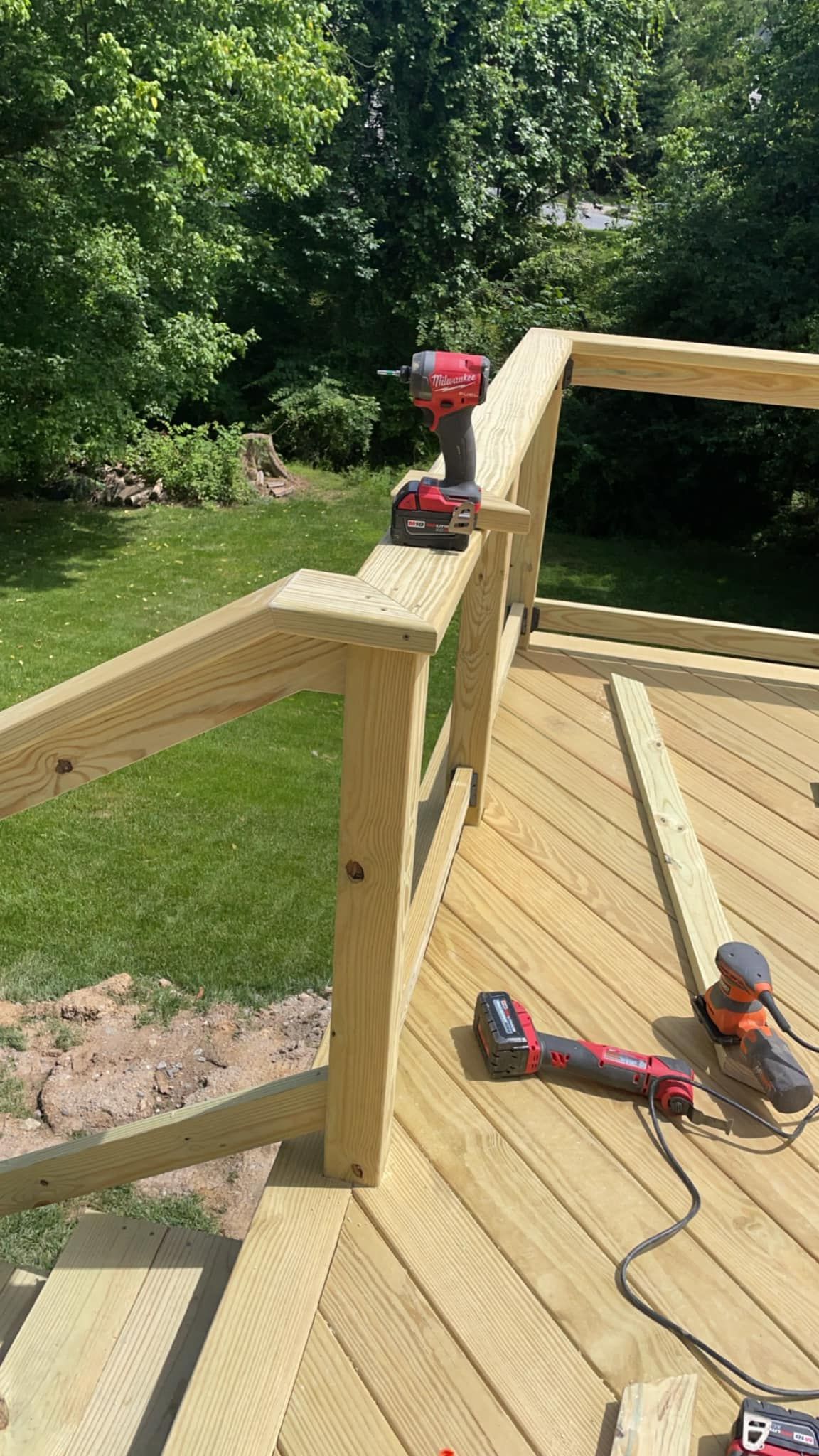 A drill is sitting on top of a wooden deck.