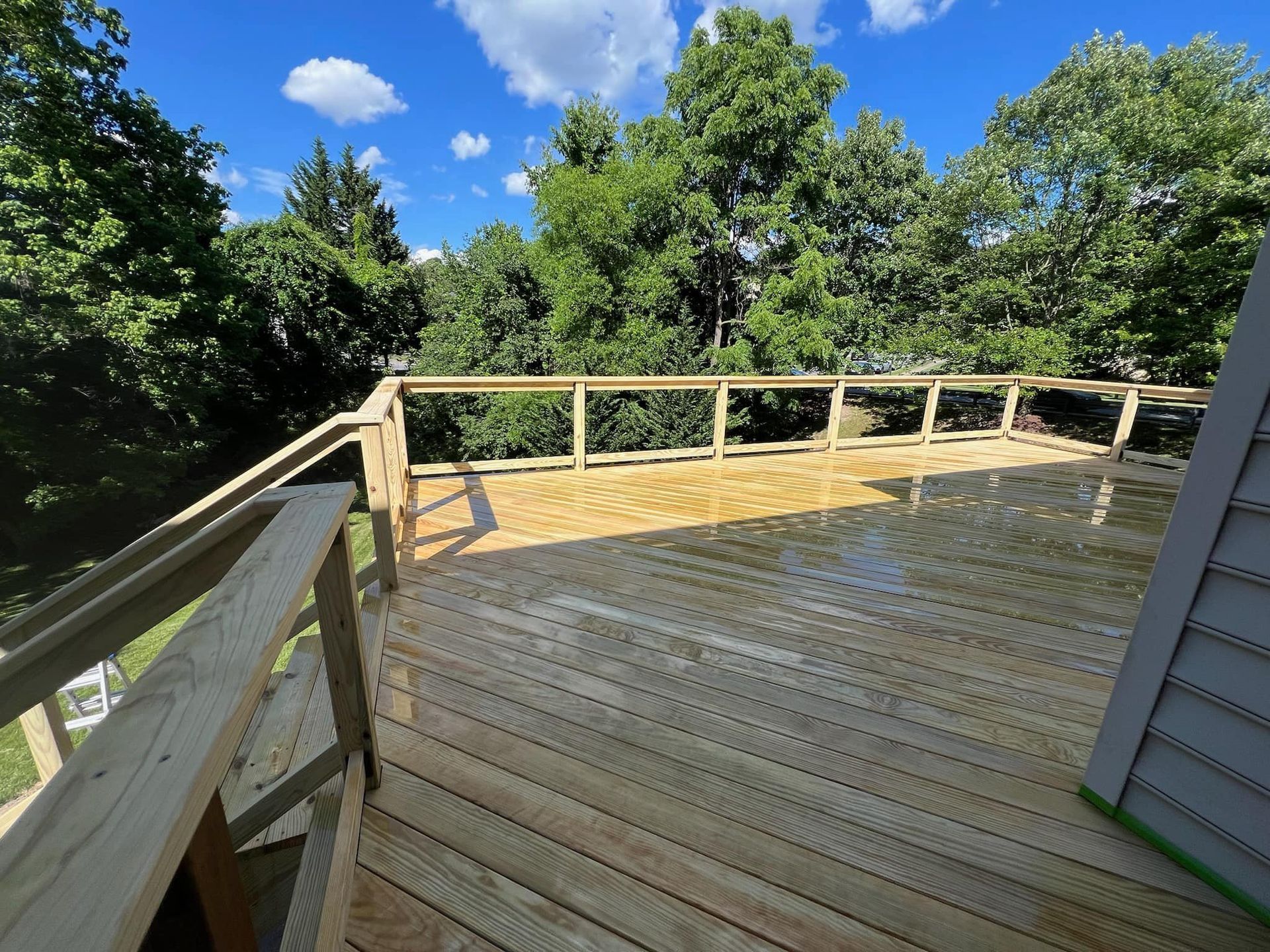 A wooden deck with a railing and trees in the background.