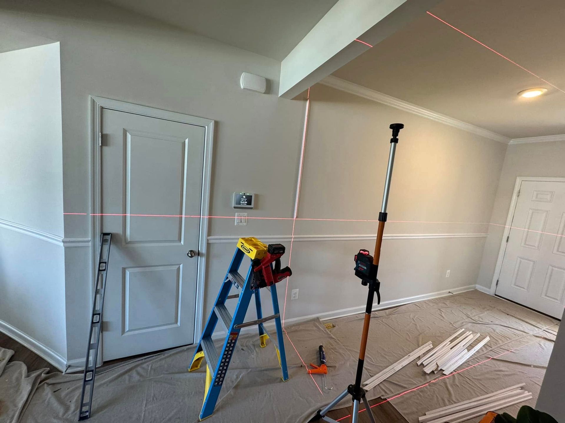 A room with a ladder and a laser level in it.