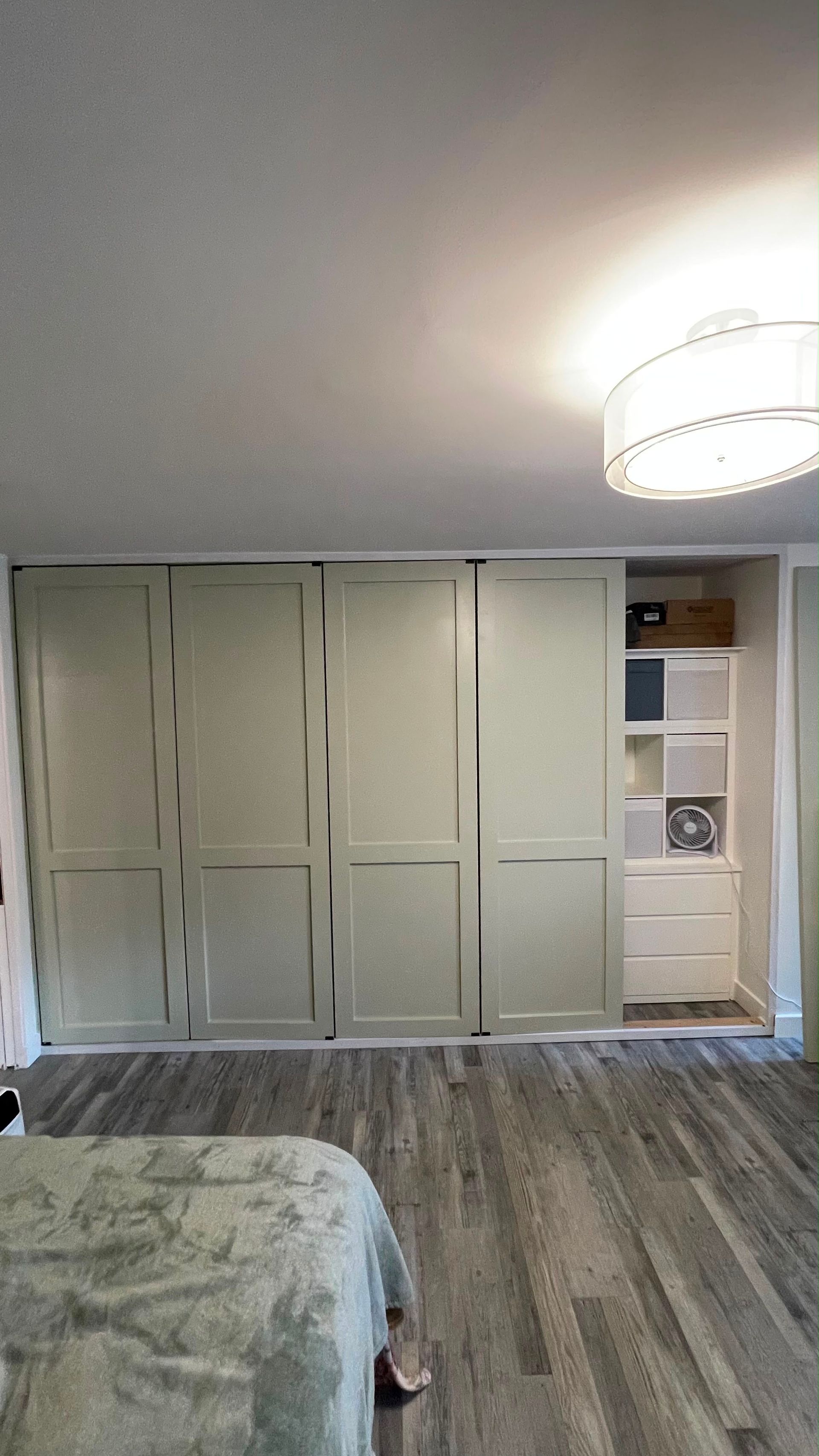 Bedroom with white built-in wardrobe, open shelves, and a hanging light fixture.
