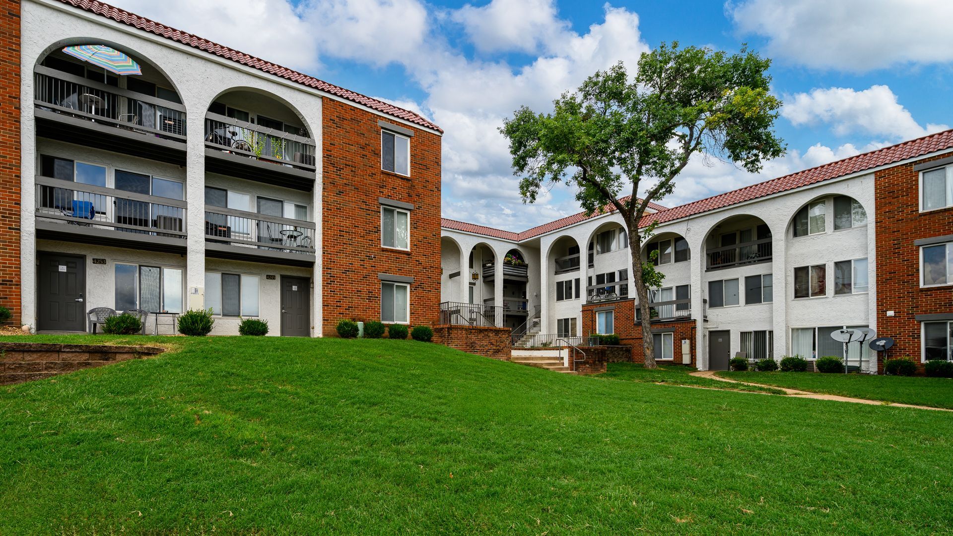 A large apartment building with a lush green lawn in front of it.