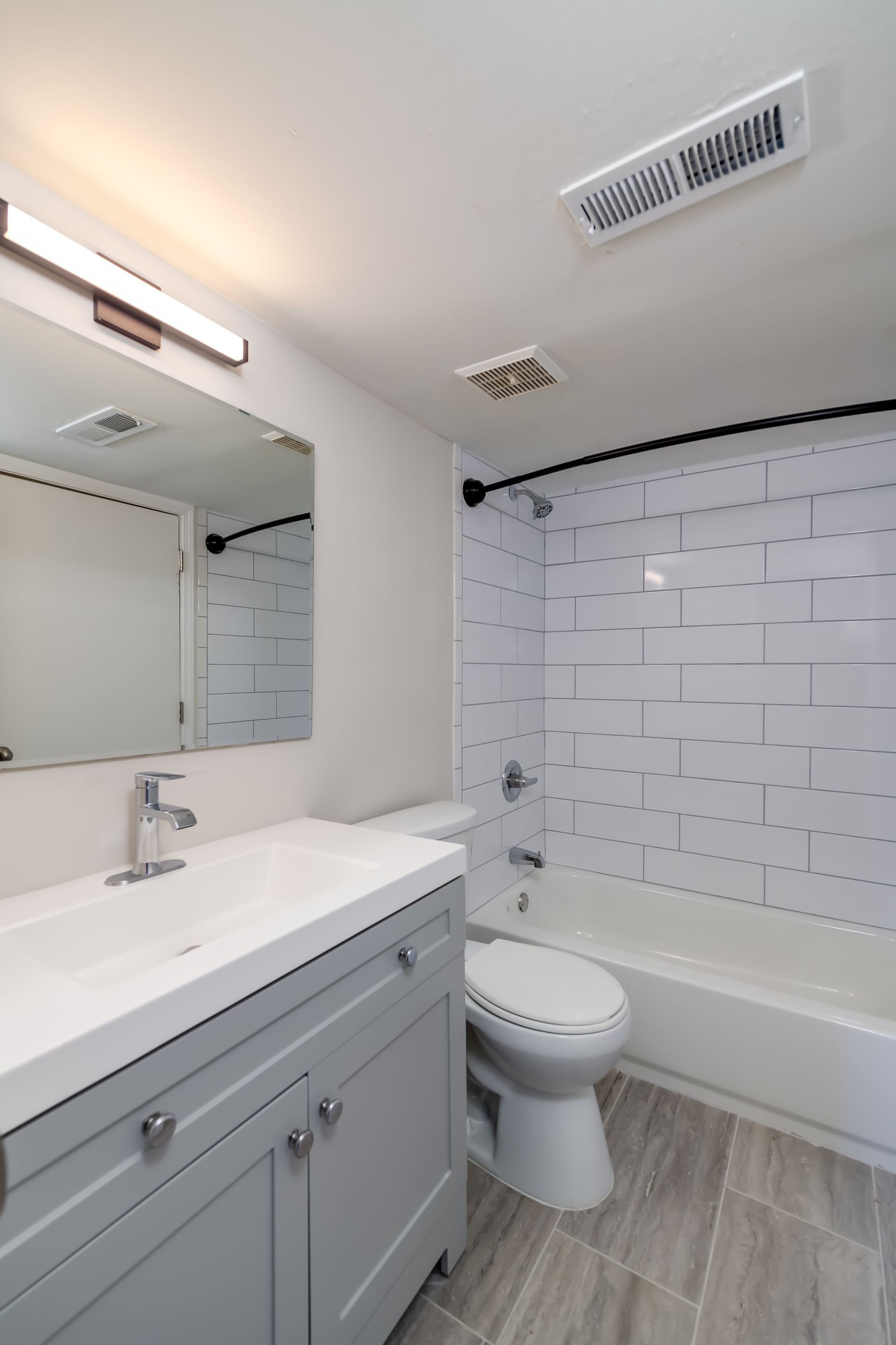 A bathroom with a sink , toilet , bathtub and mirror.