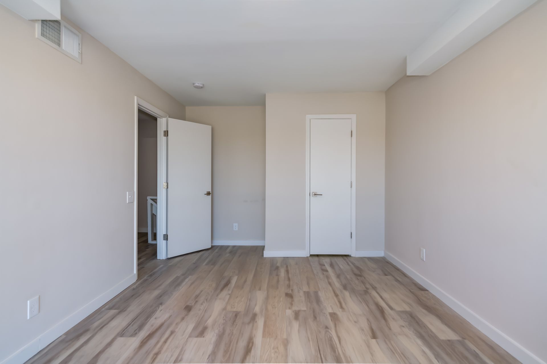 An empty room with hardwood floors and white walls