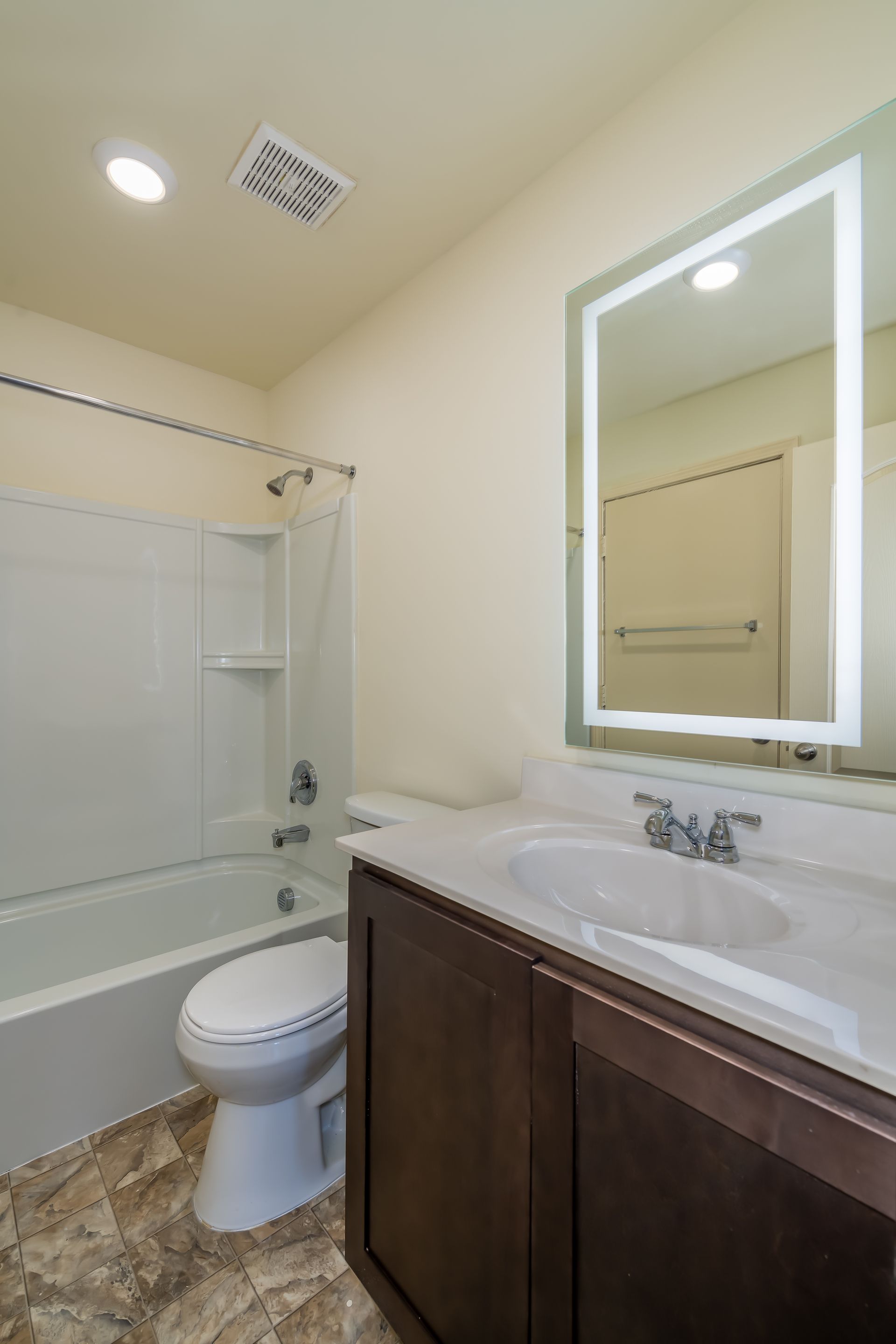 A bathroom with a toilet , sink , bathtub and mirror.
