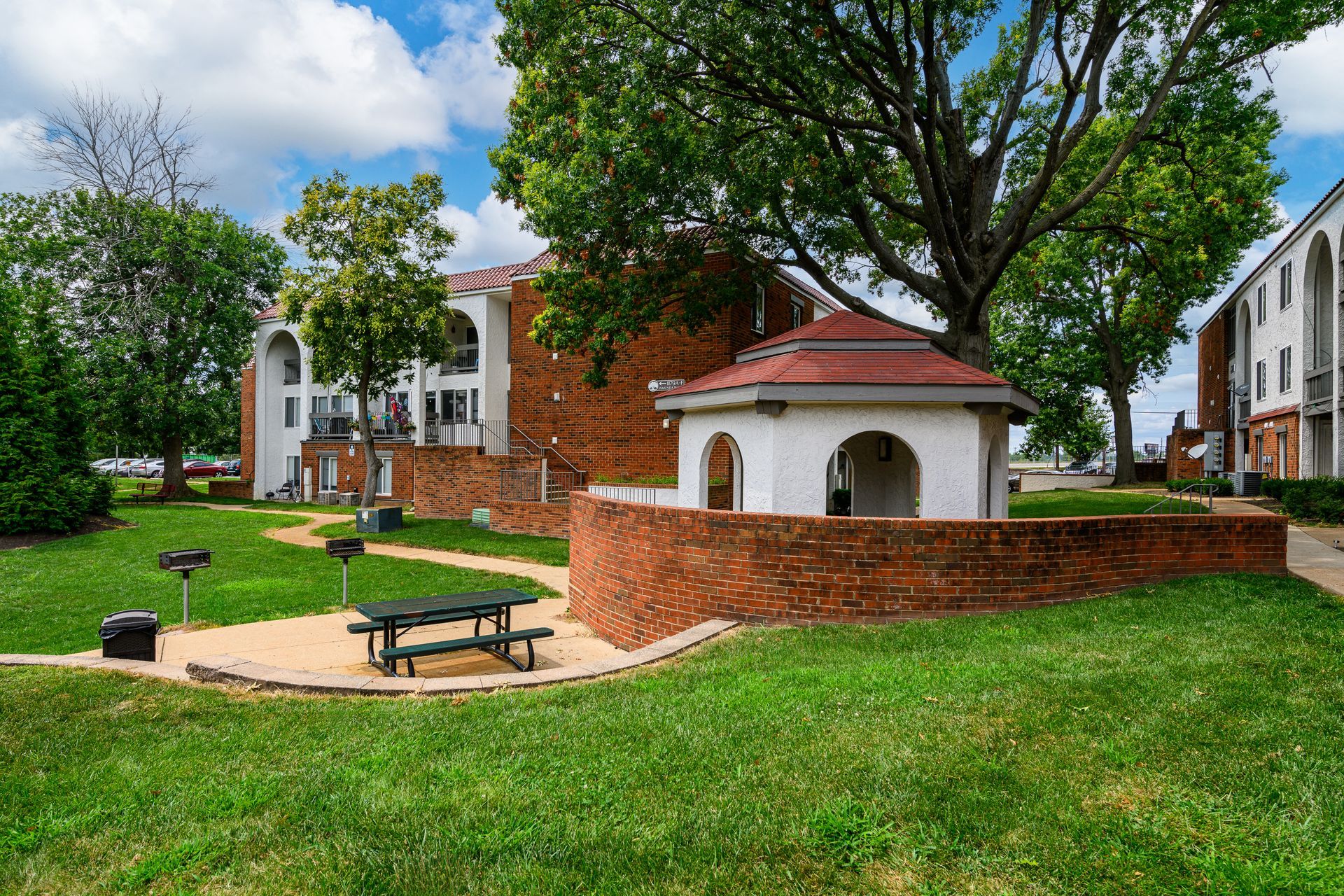 There is a picnic table in the middle of the grass in front of a building.