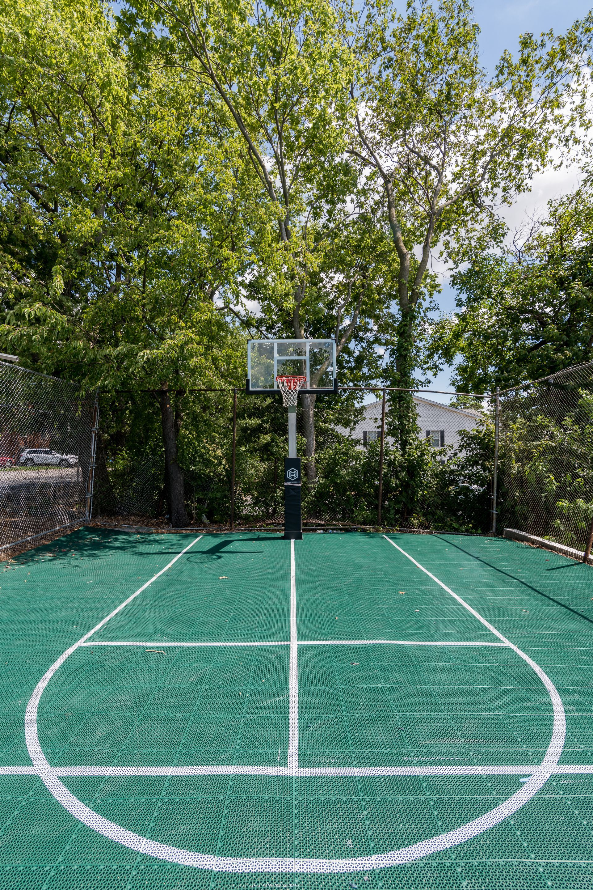 A basketball court surrounded by trees on a sunny day.