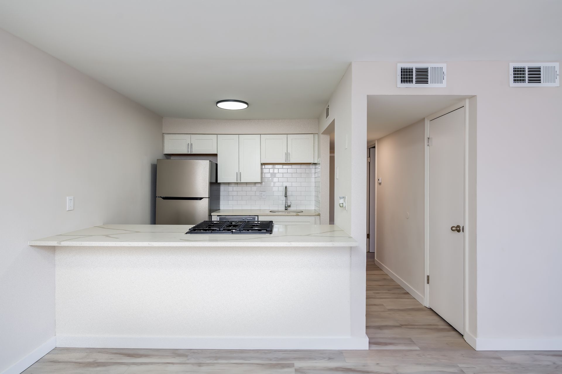 An empty apartment with a kitchen and a refrigerator