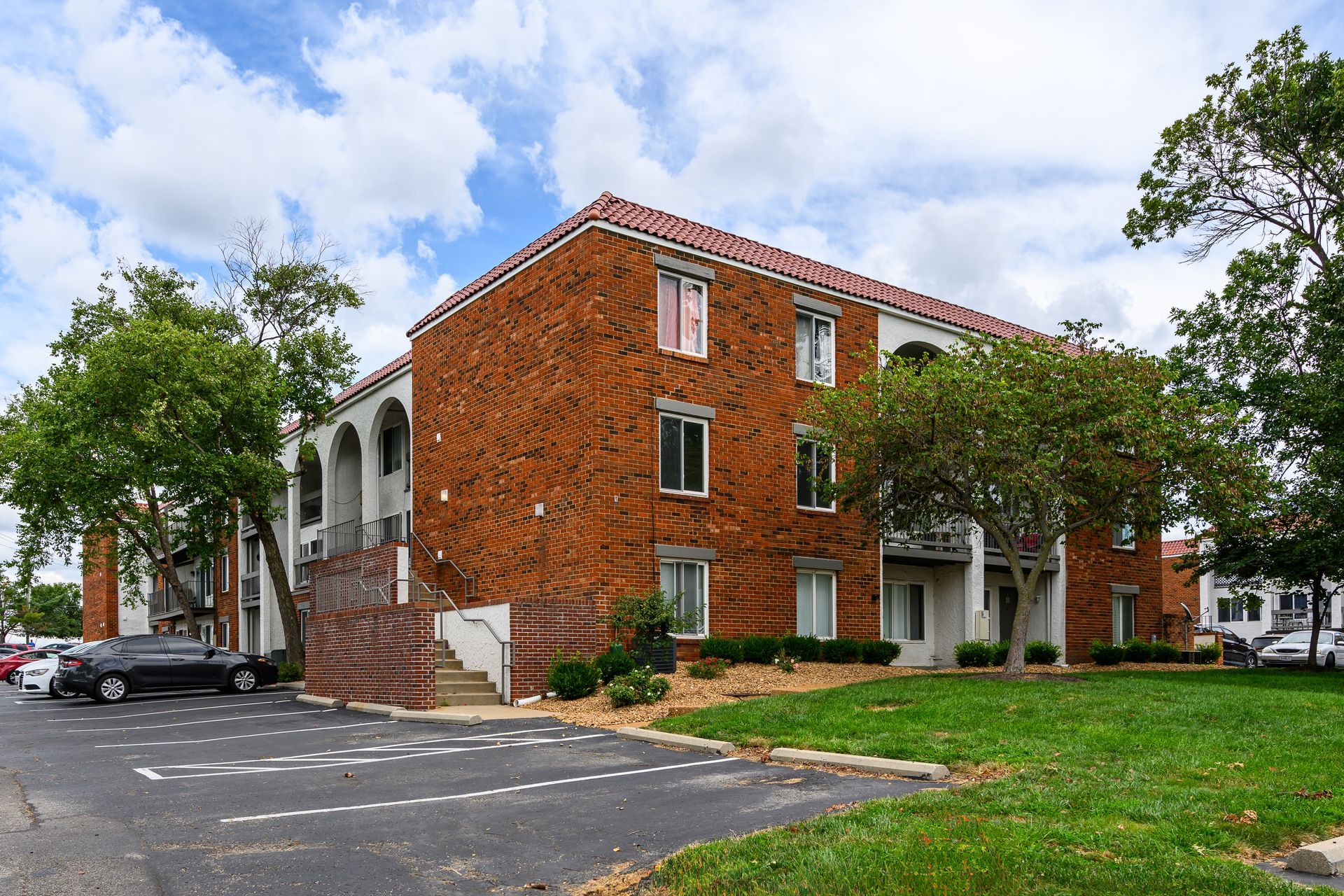 A brick apartment building with cars parked in front of it