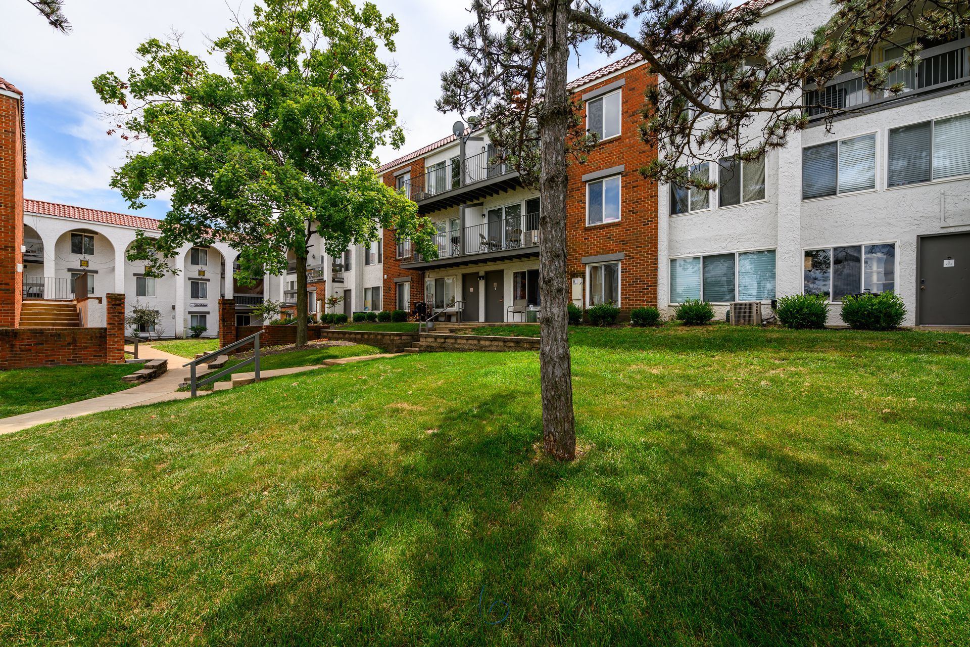 A large apartment building with a lush green lawn in front of it.
