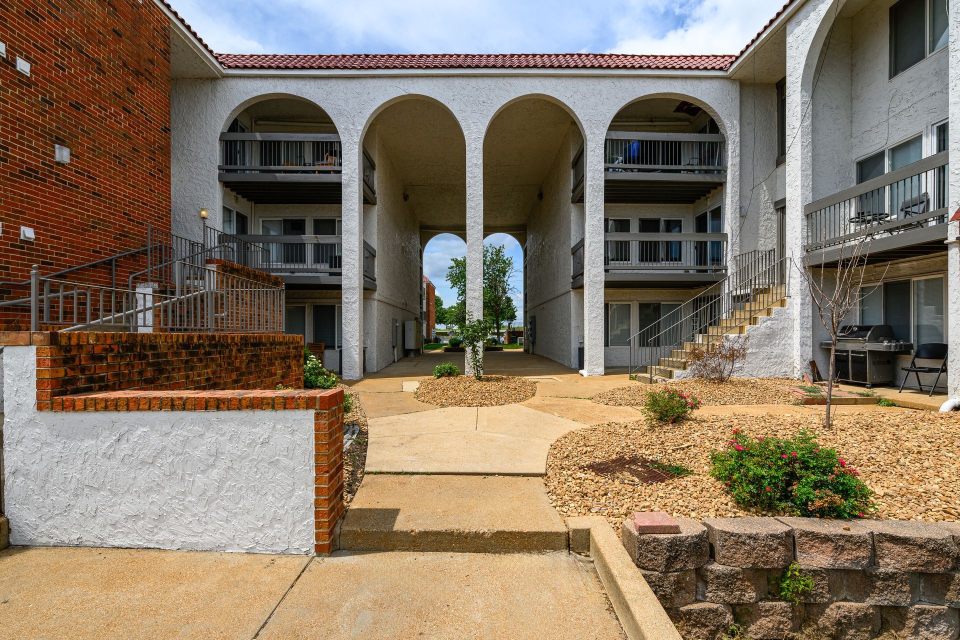 A large white apartment building with arches and stairs
