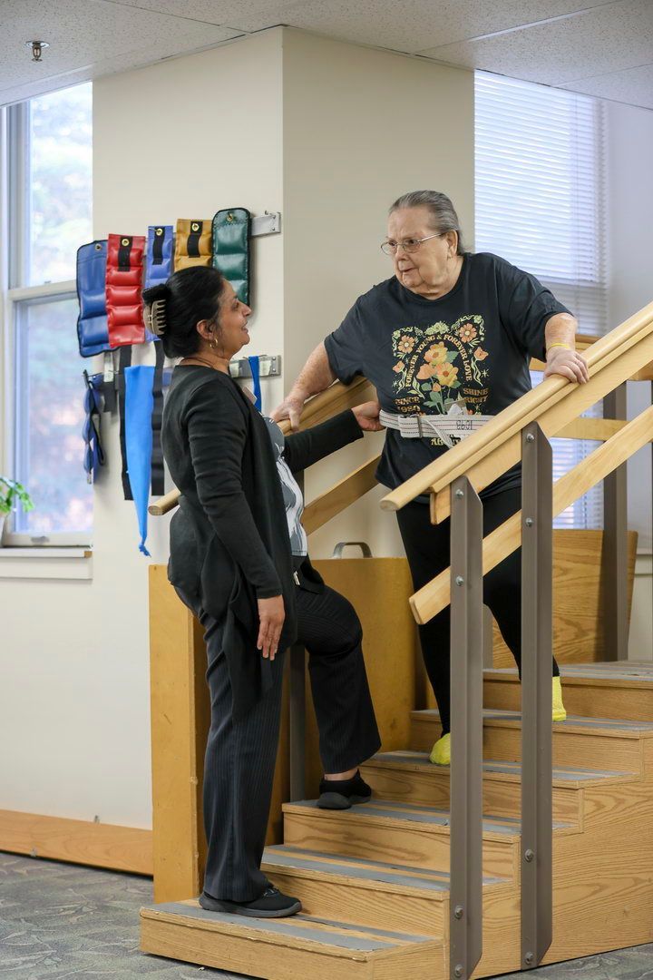 Caring nurse supporting elderly male resident outdoors at Brookside Commons skilled nursing center