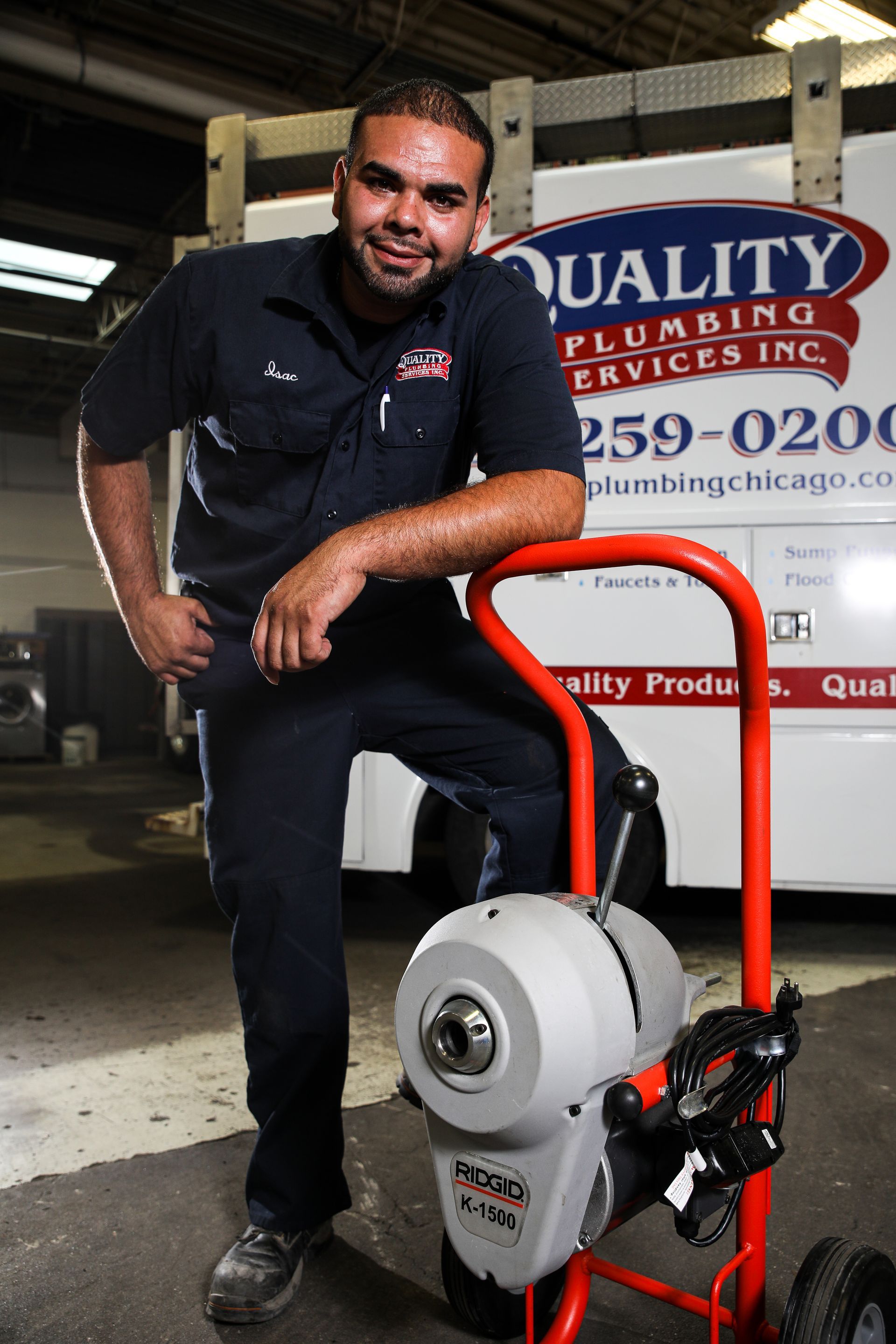 A plumber is standing in front of a quality plumbing service truck with drain cleaning equipment