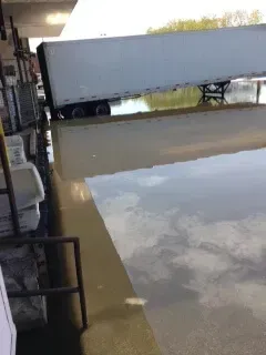 A white semi truck is sitting on top of a flooded parking lot.