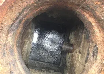 Three manhole covers are on the sidewalk in front of a building.
