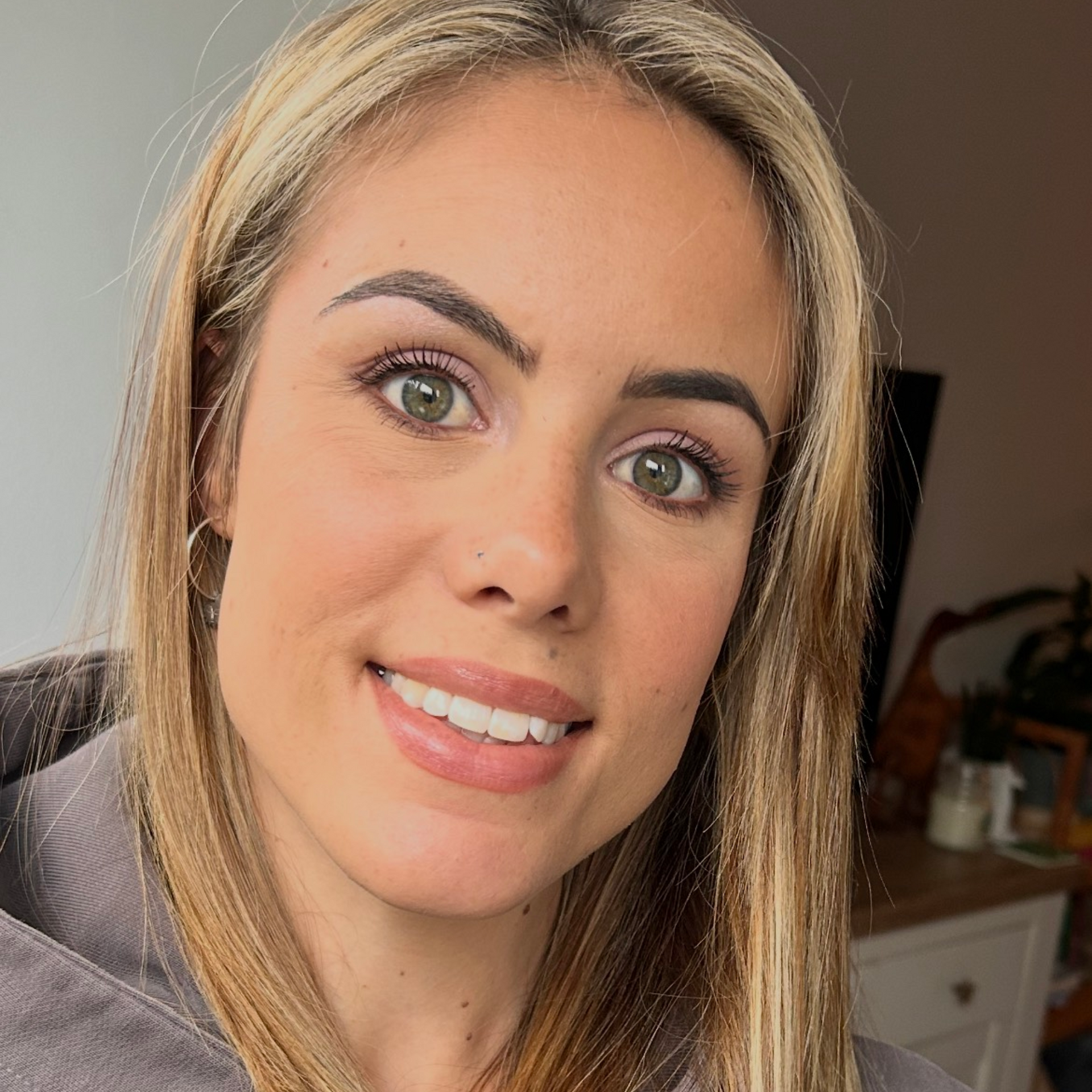 A woman in a pink sweater is taking a selfie.