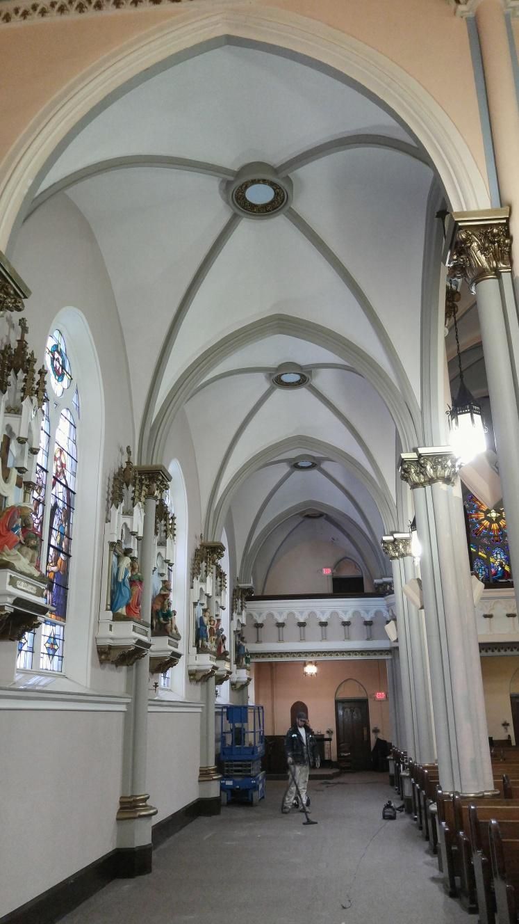 The inside of a church with a vaulted ceiling and stained glass windows.