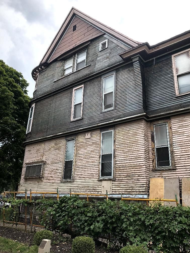 A large house with a lot of windows is sitting next to a hedge.